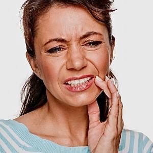 Woman with tooth or jaw pain needing emergency dental care in Morton Grove, IL
